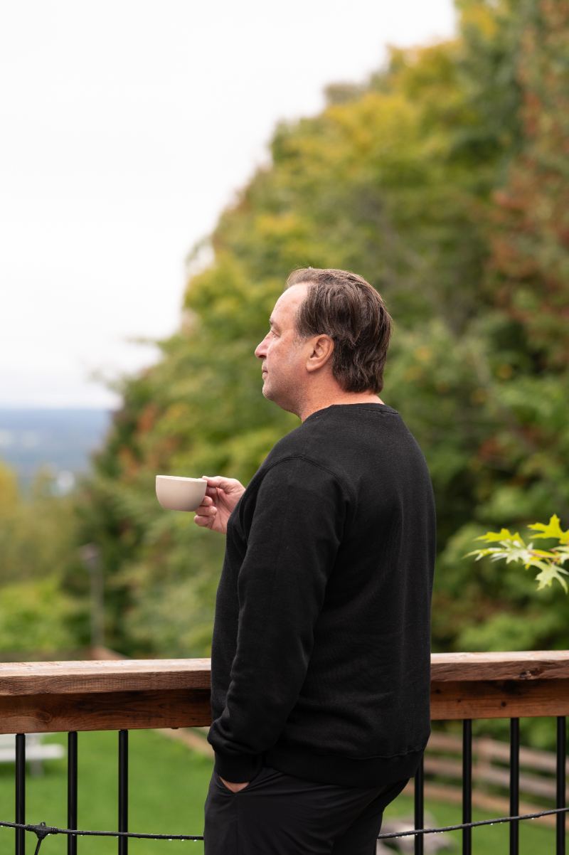 Christian Lefebvre sur la terrasse, café à la main, le regard au loin
